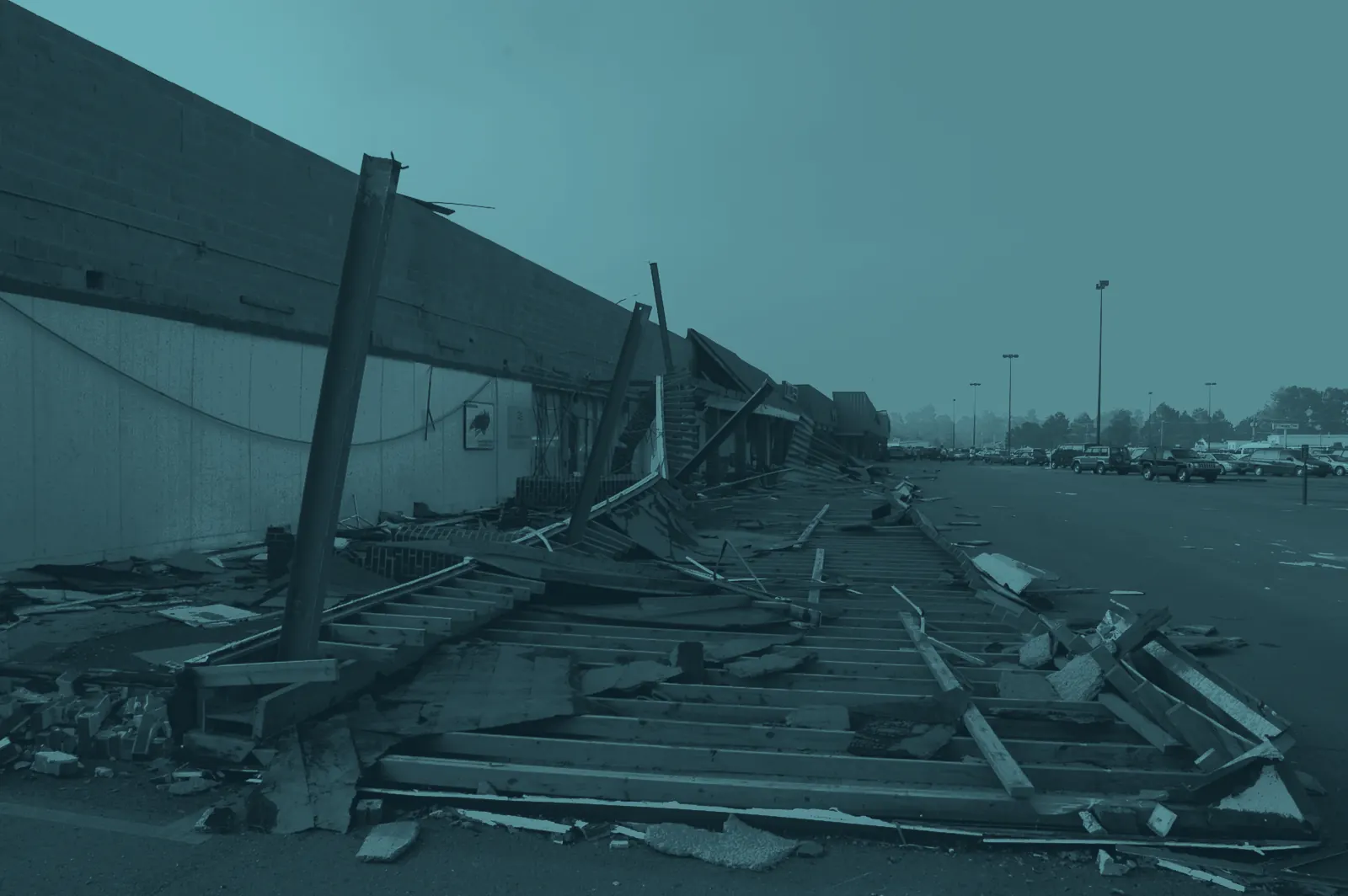 A shopping center’s walkway canopy torn down along a row of storefronts after a hurricane