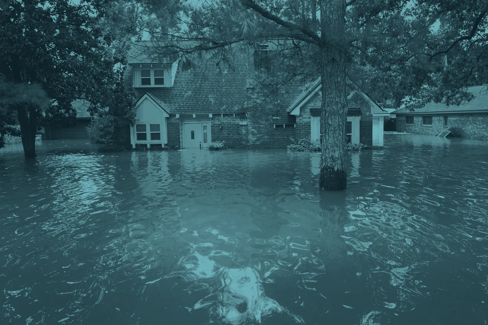 A two-storey brick house standing in brown floodwater up to its front door, after Hurricane Harvey near Houston