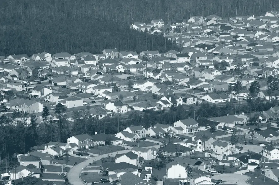 An aerial view of a neighborhood with blue tarps covering damaged roofs