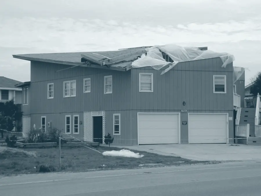 A house with a section of roof decking torn away by wind